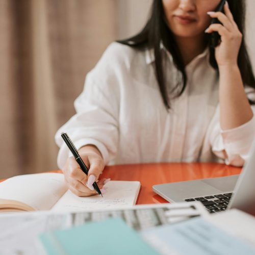 Admin lady taking notes whilst on the phone